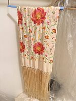Full view of shawl hanging showing embroidery and fringe
