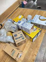 Multiple GE and Philips soft-white bulb boxes with loose bulbs on countertop