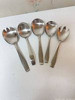 Five stainless steel Georg Jensen serving utensils laid out side by side