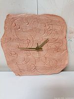Front view of peach ceramic wall clock showing embossed musical design and gold hands
