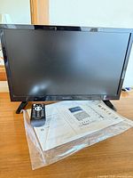 Front view of Insignia LED TV with remote and manual on tabletop
