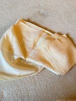 Folded ivory linen tablecloth and stacked napkins on carpet