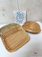 Group view of three wicker baskets and ceramic tile trivet