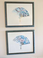 Both framed fan prints hung on wall