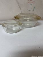 Two Pyrex covered glass bowls side-by-side showing overall shapes and sizes