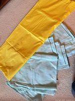 Yellow solid tablecloth with folded aqua napkins underneath