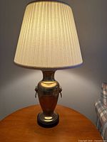 Full view of brass table lamp with shade on wooden table