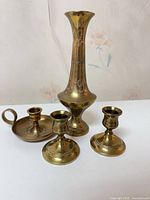 Complete brass set: tall vase, pair of candlesticks, handled chamberstick