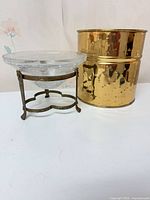 Glass bowl on brass stand beside hammered brass planter