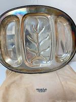 Full view of oval silver-plated three-section tray on retailer cloth