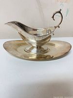 Side view of silver-plated gravy boat on underplate