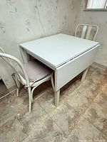 Table folded on one side with chair tucked in shows overall structure and colour