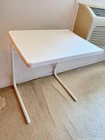 Front view of white TV tray showing tabletop and cantilever frame