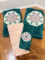 Two teal bath towels, peach hand towel, teal hand towel displayed