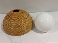 Rattan dome shade beside white glass globe