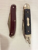 Two closed pocket knives side by side showing handles and bolsters