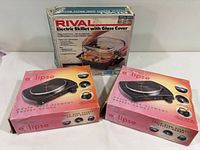 Three boxed appliances: two Toastmaster Eclipse hot plates, one Rival electric skillet