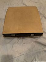 Beige hard carrying case closed with handle visible