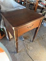 Overall view of closed wood sewing cabinet showing wear on corners