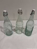 Front view of three aqua glass bottles with swing-top stoppers