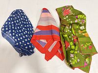 Three scarves folded displaying patterns and colours