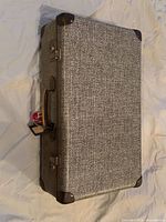 Closed suitcase showing exterior, handle, latches, luggage tag and corner protectors