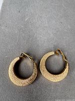 Pair of gold tone hoop earrings front view showing texture and clip backs