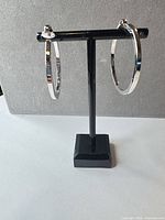 Front view of both silver hoop earrings on stand