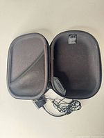 Open Bose case showing interior pocket, molded cradle, adapter and cable