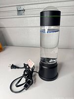Full view of bubble water lamp showing black base, clear body, beads and power cord