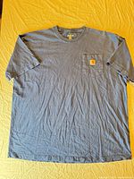 Full view of front of blue Carhartt pocket T-shirt laid flat