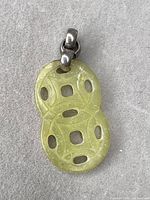 Front view of carved light yellow-green jadeite pendant with bail