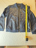 Full front view of navy quilted bomber jacket with measuring tape for scale