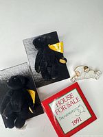 Overview of two teddy bear pins, enamel cherub pin and red display folder