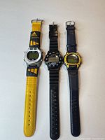 Front view of three digital wristwatches showing faces and straps