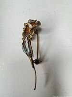 Front view gold-tone floral filigree brooch with stem and leaves