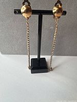 Front view of clip-on earrings on stand showing full length and rhinestone chains