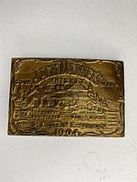 Front view of brass buckle showing full relief design and inscriptions