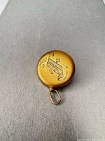 Front view showing gold-tone engraved monogram and swivel hook