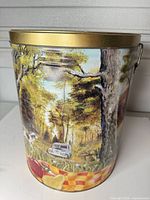 Front view of cylindrical Land Rover tin canister showing forest scene, vehicle and picnic graphics