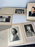 Five matted portraits displayed on table: sailor, two wedding groups, two female portraits