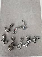 All eight silver-tone charms laid out on grey surface