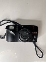 Front view of Olympus SuperZoom 3000 DLX showing lens, flash and wrist strap