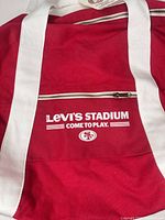 Front view of red duffel showing Levi's Stadium graphics and front zip pocket