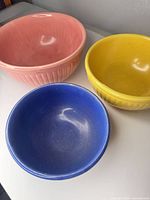 Front angled view of all three ribbed ceramic bowls showing colors and exterior fluting