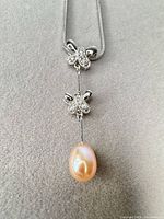 Full view of necklace showing chain, CZ bow motifs and pearl drop