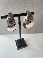 Front view of both silver-tone hoop clip-on earrings on stand