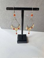 Front view of both earrings hanging on stand