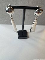 Front view of silver-tone dangle earrings on stand
