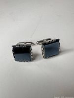 Front view of both cufflinks showing hematite inlay and square form